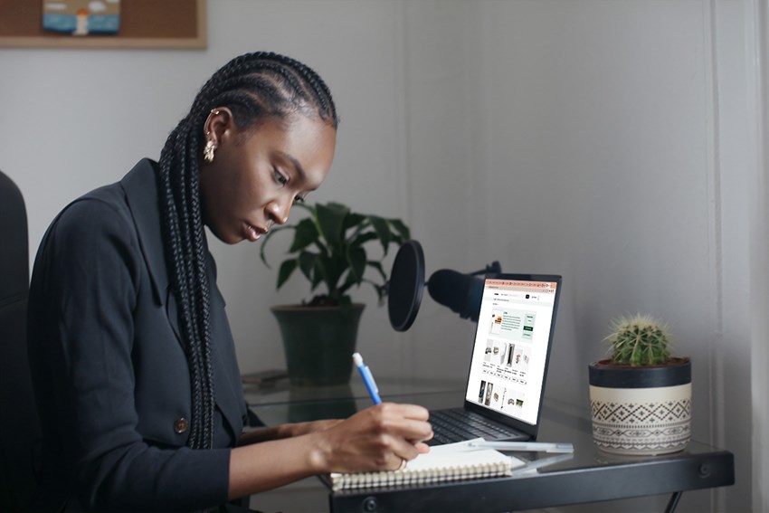 Girl with braids browsing for content online and writing on book