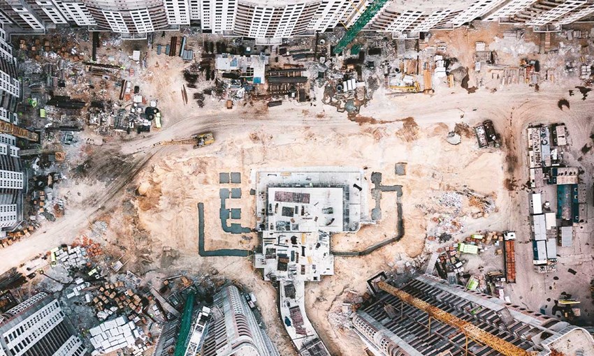 A large-scale construction site with surrounding buildings and containers of building material