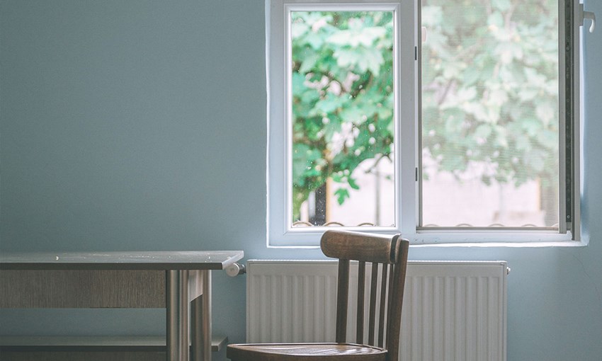 A chair and a table positioned in front of an open window with a tree outside. Concept fresh, healthy air