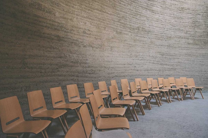 Sedie marroni in anfiteatro con sfondo muro grigio in cemento